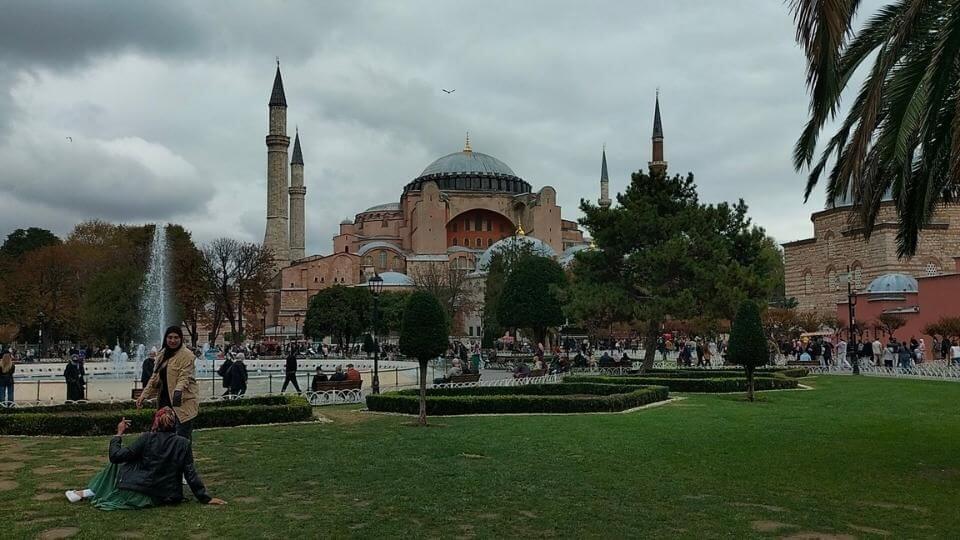 An exterior view of the Hagia Sofia and gardens surrounding it on a cloudy day in Istanbul.