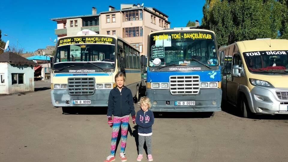 Ayla and Romy standing in front of buses at the bus station in Kars during our Turkey to Georgia road trip