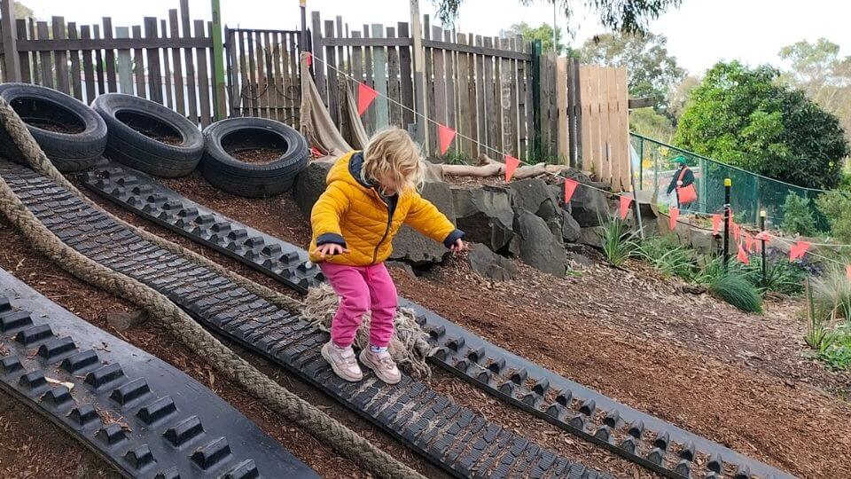 Romy climbing the play structures made from tires at the CERES Community Park playground in Brunswick East