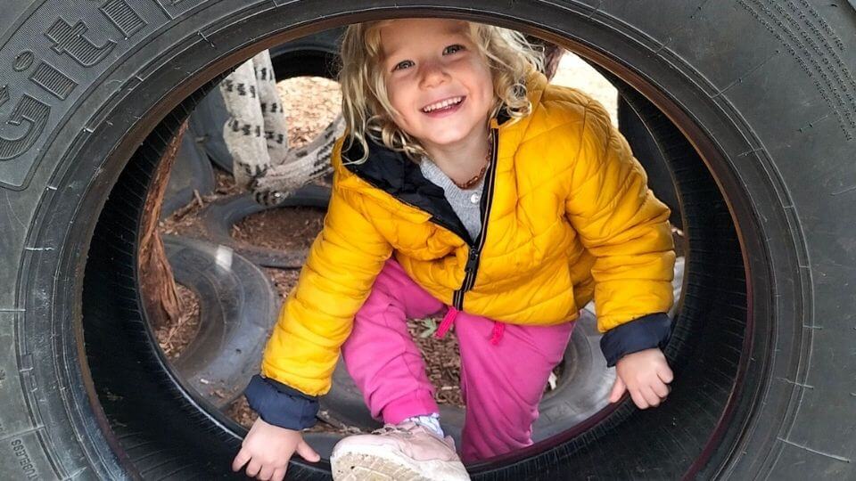 Romy playing in one of the tires at the CERES community park playground in Brunswick East