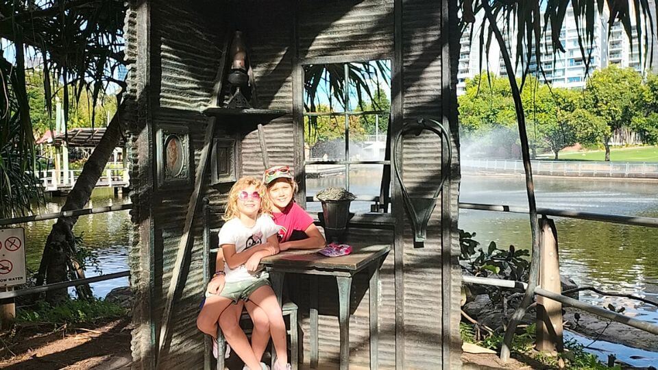 Ayla and Romy at a little table on the lakeside at the Roma Street Parkland in central Brisbane.