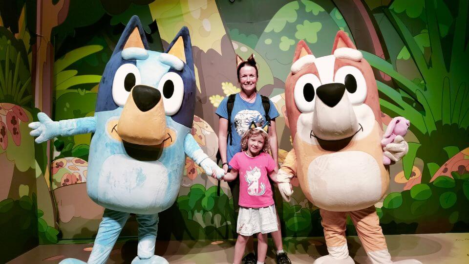 Elly and Romy get a photo with Bluey and Bingo at Bluey's World in Brisbane.