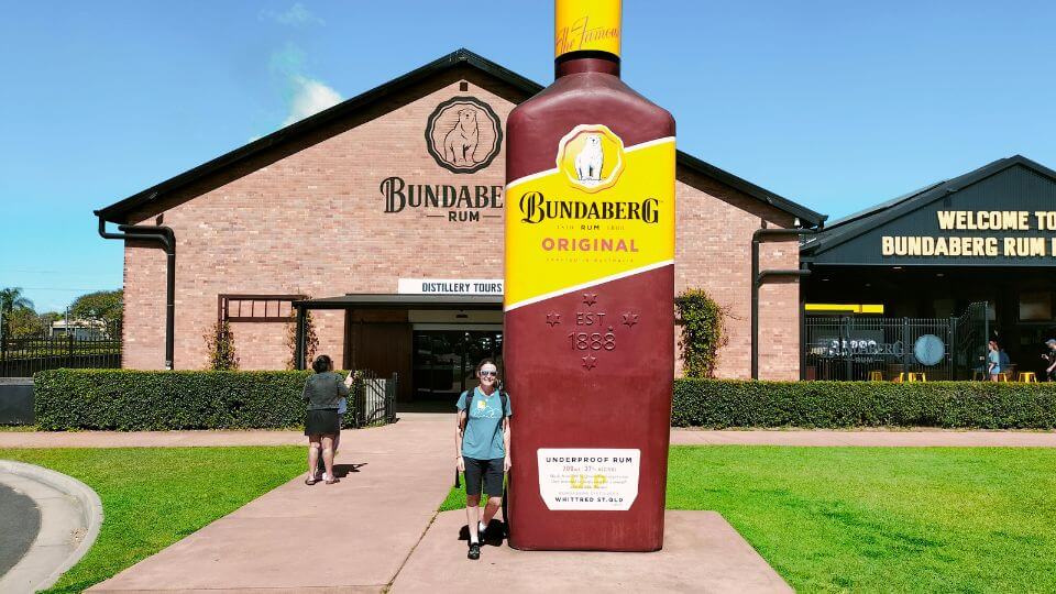 Elly standing next to a giant bottle of rum outside the Bundaberg rum distillery, one of the area's top attractions.