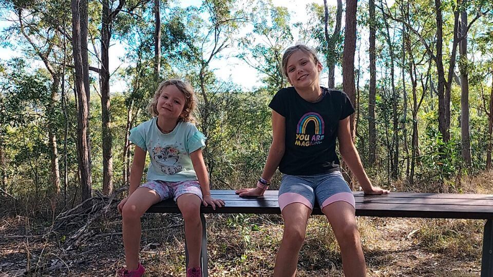 Romy and Ayla sitting on a bench at the Russo Nature Park, one of the best things to do in Childers, Queensland.