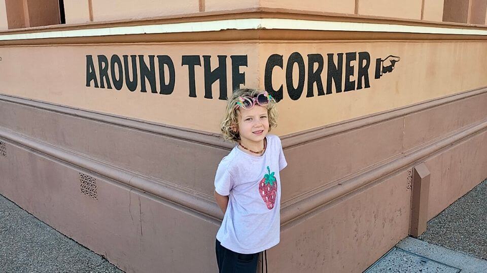 Romy standing in front of the Around the Corner sign at The Story Bank in Maryborough.