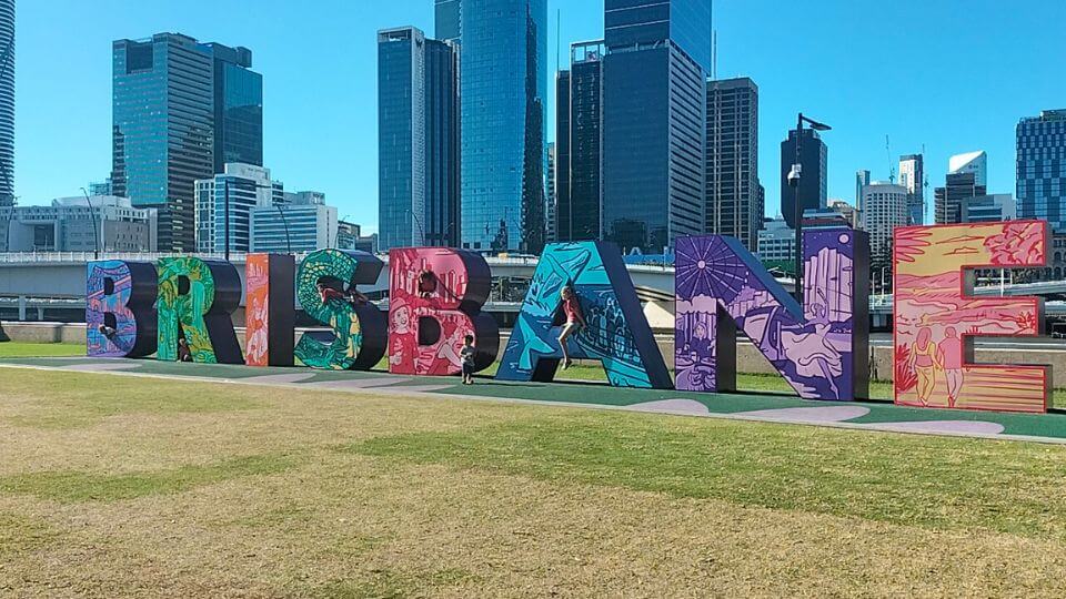 The Brisbane sign at Southbank with city buildings behind.