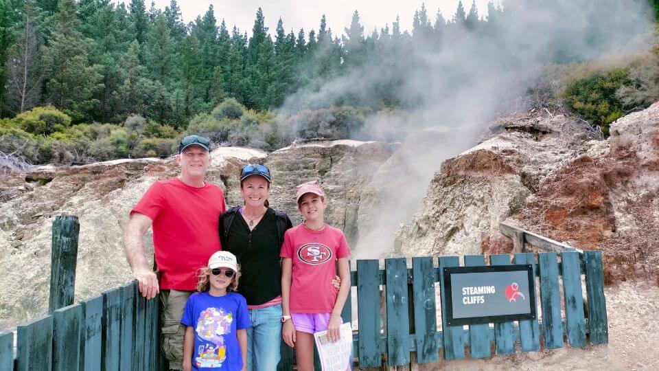 Colin, Elly, Romy, and Ayla stop for a photo in front of one of the geothermal features at Hell's Gate.