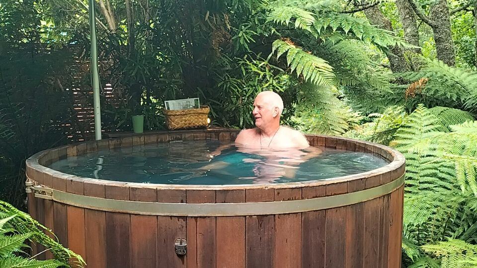 Colin relaxes in a Secret Spot Hot tub surrounded by lush greenery.