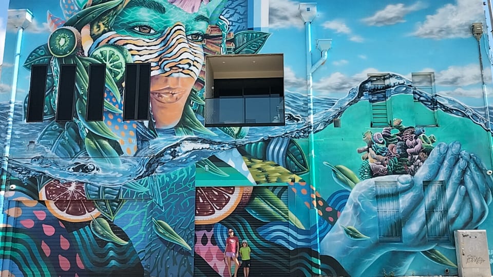 Ayla and Romy appear tiny standing in front of one of Townsville's most spectacular street art locations.