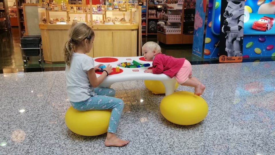 Ayla and Romy play in a kids' play area at an airport.