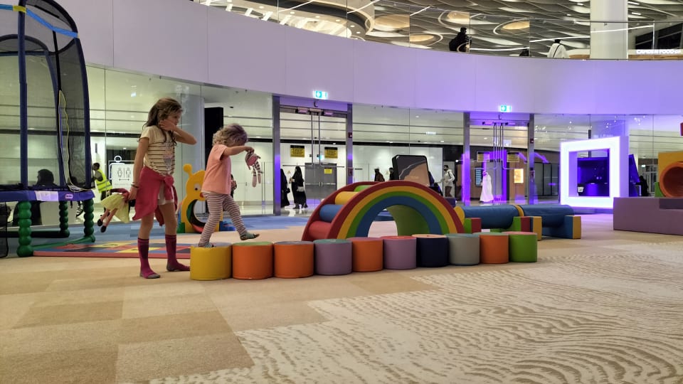 Ayla and Romy play in an airport play area.