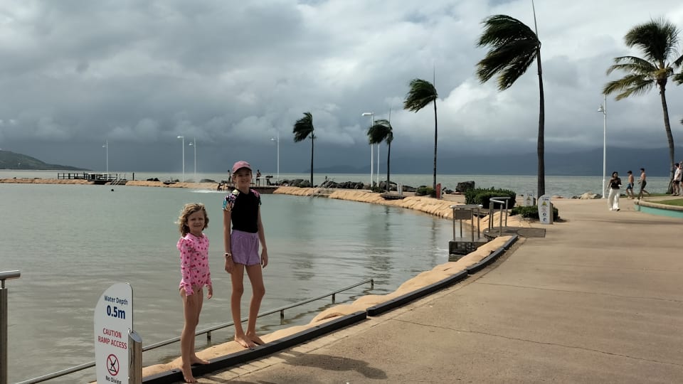 Ayla and Romy stand next to the Rockpool on The Strand in Townsville on a stormy day.