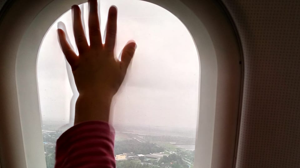 Ayla's hand up against an airplane window.