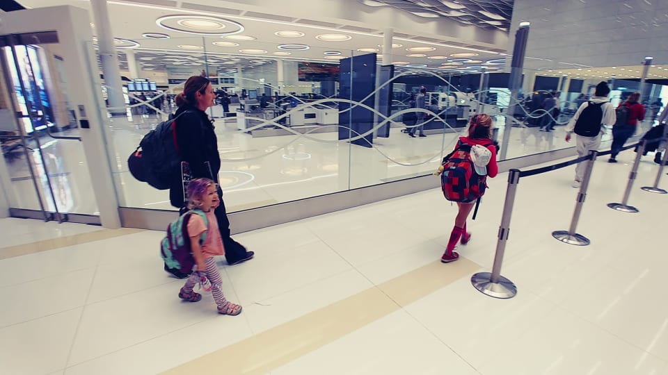 Elly, Ayla, and Romy walk through an airport.