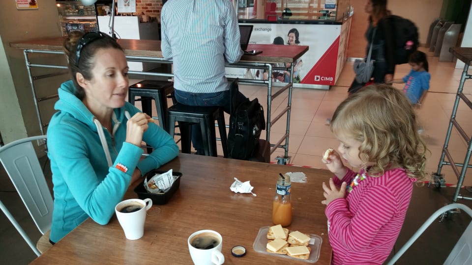Elly and Ayla with cups of coffee and cheese on crackers at an airport on travel day.