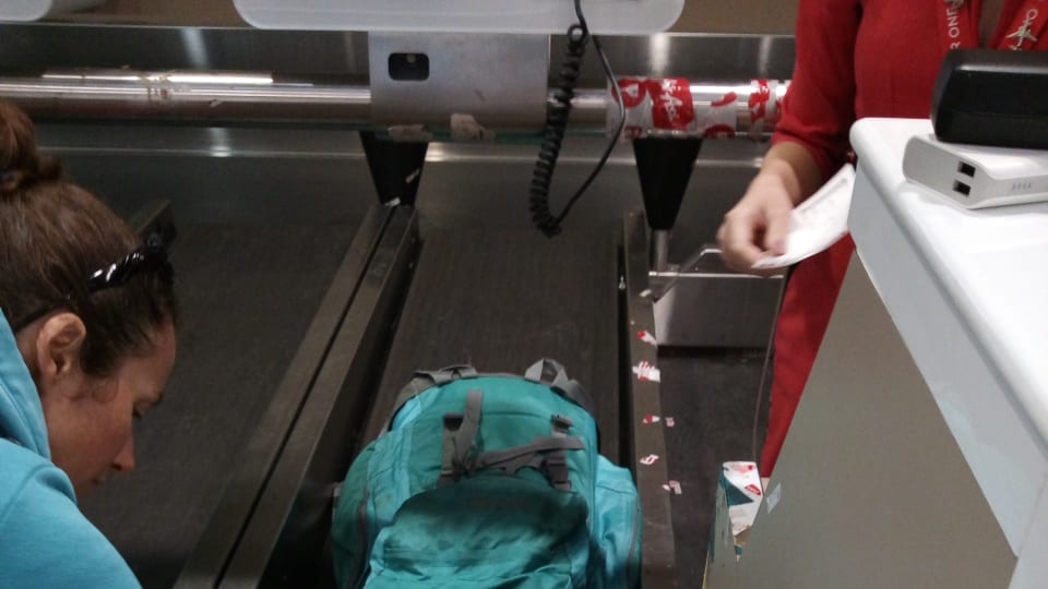 Elly prepares her backpack for loading onto a conveyor belt and weighing at an airport