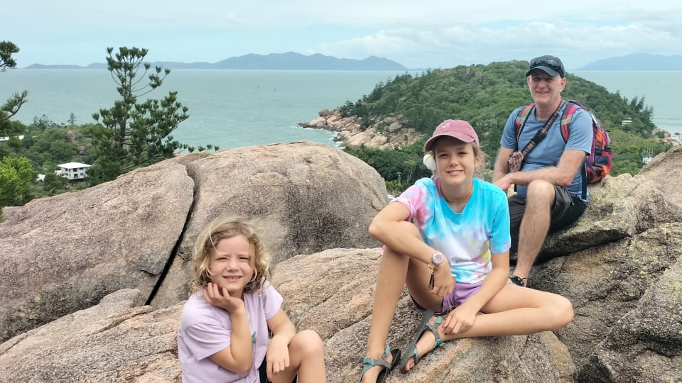 Romy, Ayla, and Colin sit on rocks at the Arcadia Lookout on Magnetic Island.