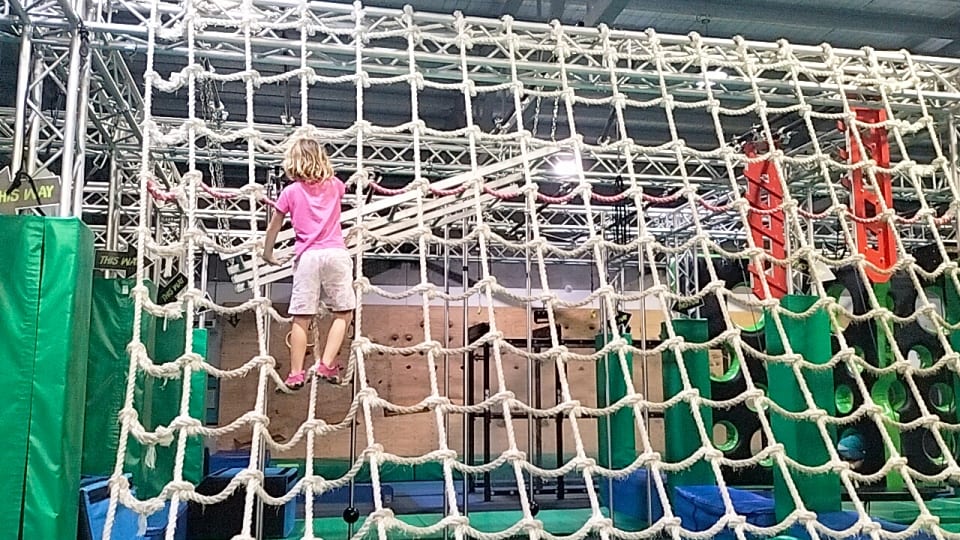 Romy climbs up a net at Ninja Parc Townsville.