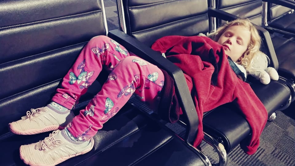 Romy sleeps on airport chairs.