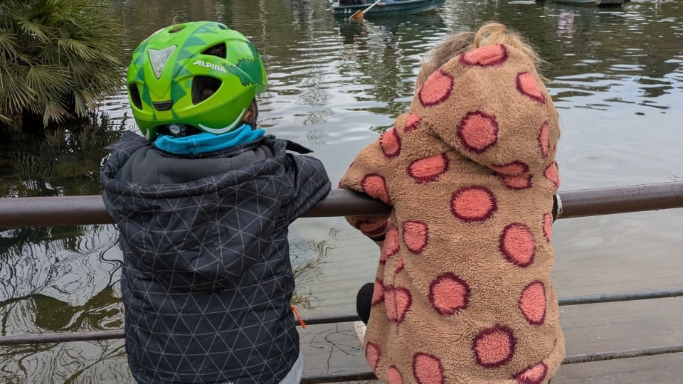 Two kids watch people in boats on the water in Barcelona, a family-friendly city in Spain.