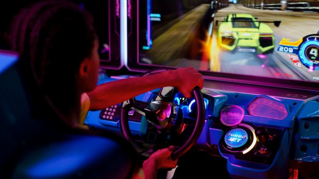 A person playing an immersive arcade racing game with vibrant lights.