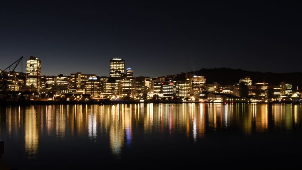 A captivating panorama of Wellington’s skyline at dusk, city lights shimmering across the harbor and highlighting modern architectural landmarks.