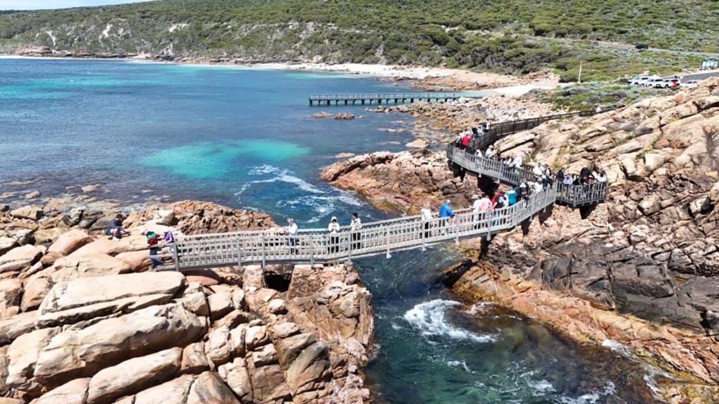 Aerial view of tourists exploring the Cape Naturaliste scenic walkway along the rugged Western Australian coast.
