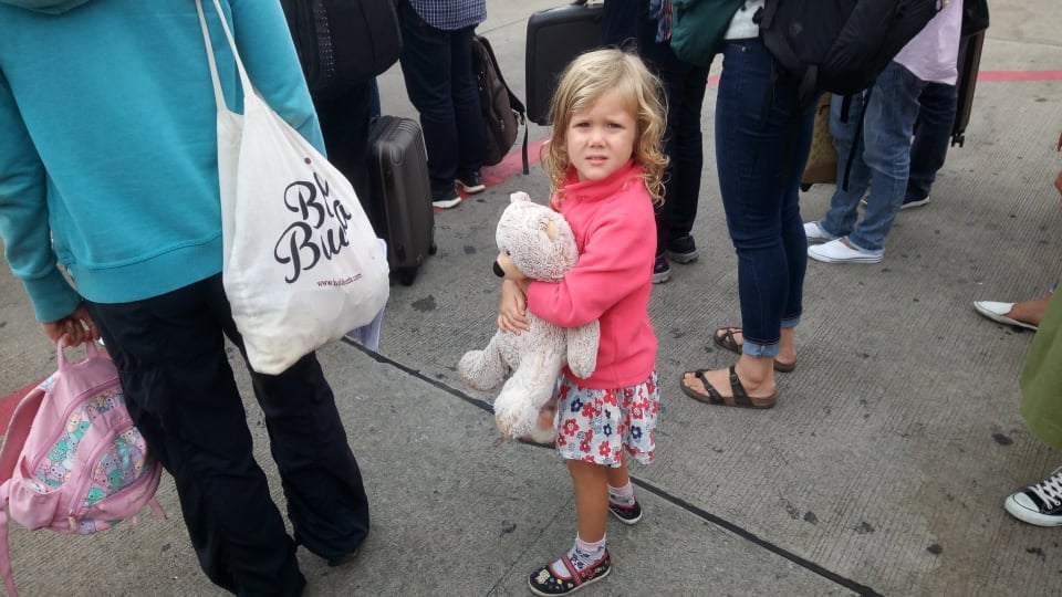 Ayla holds her teddy bear while waiting in line to board a flight.