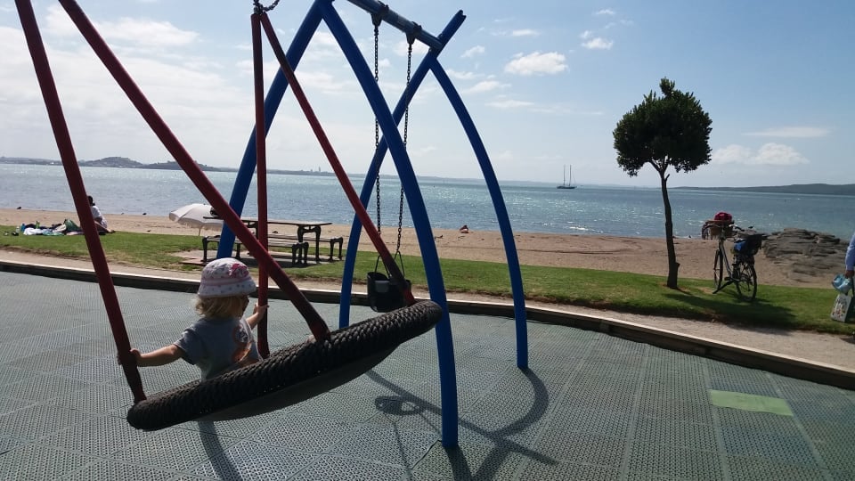 Ayla plays on a playground swing at St Heliers Beach in Auckland.