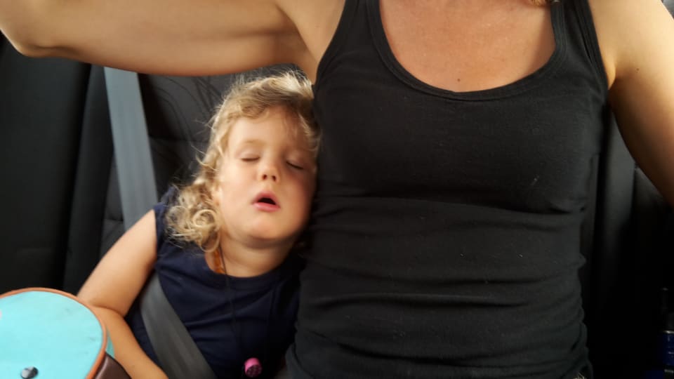 Ayla sleeps under Elly's armpit in the back of a car.