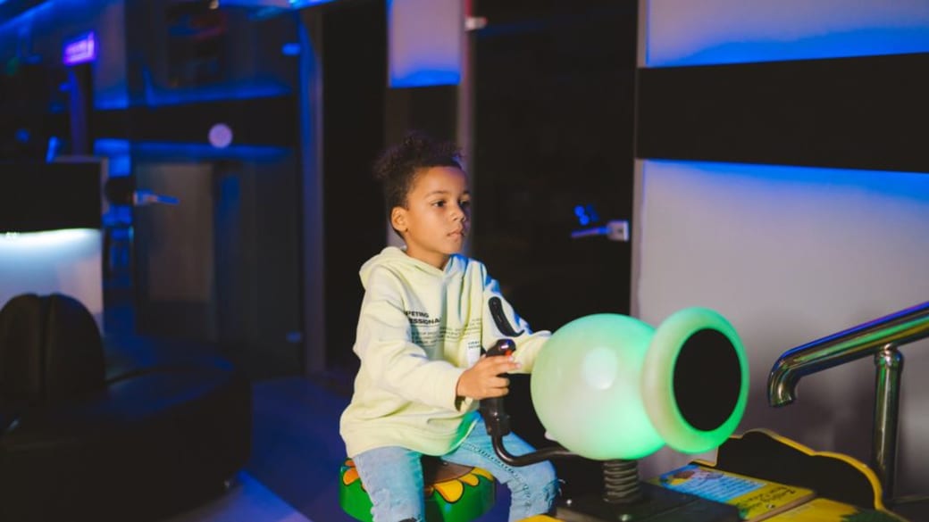 Child playing a video game in an arcade, focused on the screen.
