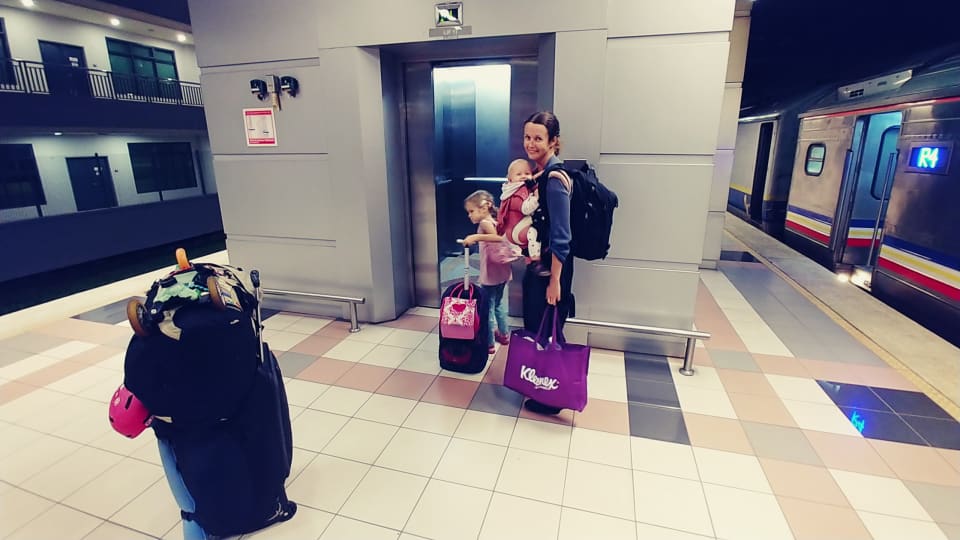 Elly, Ayla, and Romy with all their luggage at a train station on a family travel day.