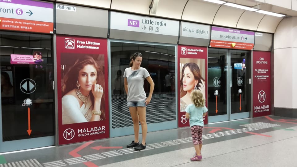 Elly and Ayla wait for an underground train at Little India station in Singapore.