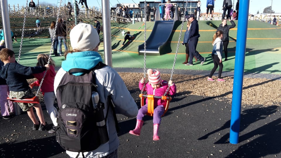 Elly pushes Ayla on a swing at the Margaret Mahy Playground in Christchurch.