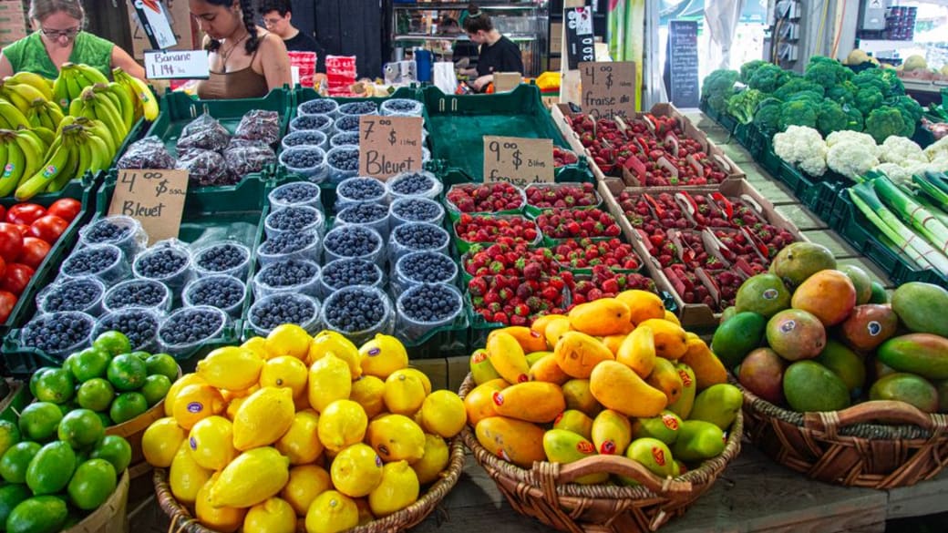Fresh fruits and vegetables beautifully arranged at an outdoor market stall, showcasing a variety of produce and healthy options.