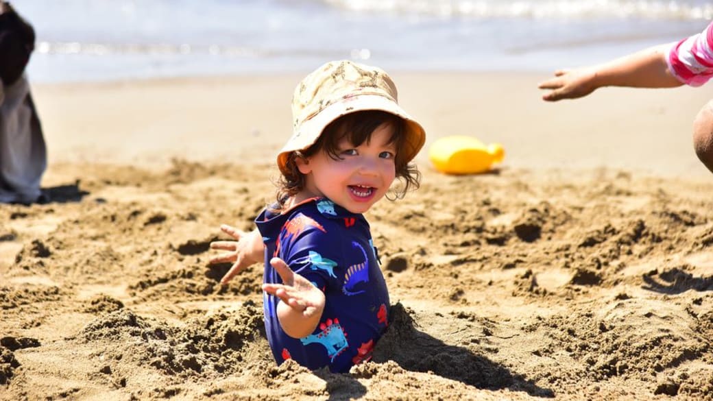 Joyful kid playing on a bright, sandy beach, soaking up the summer sun.