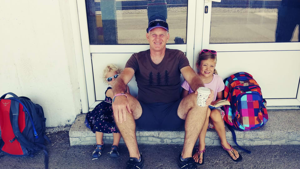 Romy, Colin, and Ayla sit on a doorstep at a train station on a travel.day