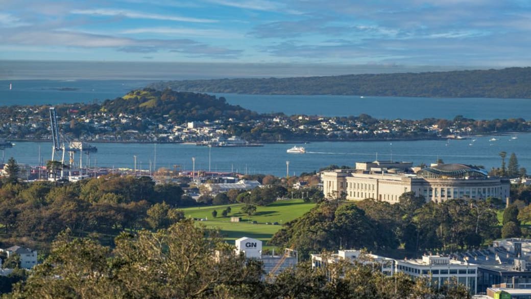 Panoramic view of Mount Eden with Auckland city skyline and Sky Tower in the background on a sunny day.