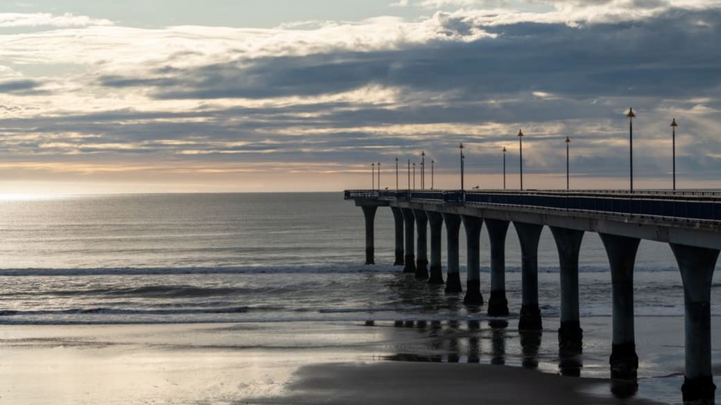 Stunning sunset over New Brighton Pier in Christchurch, New Zealand, capturing serene beach vibes and dramatic skies.