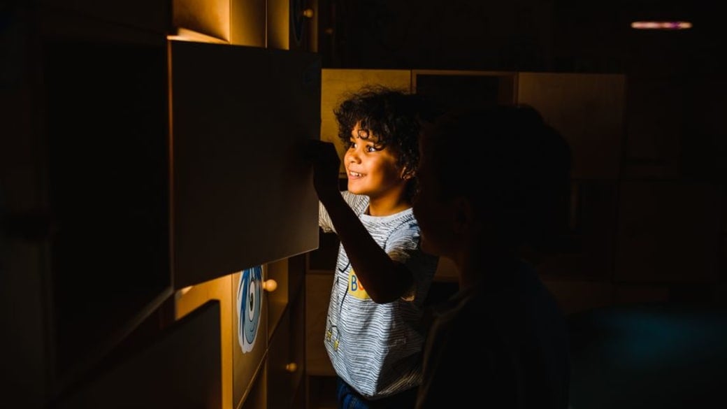 Two children interact with an illuminated educational exhibit, demonstrating curiosity and discovery.