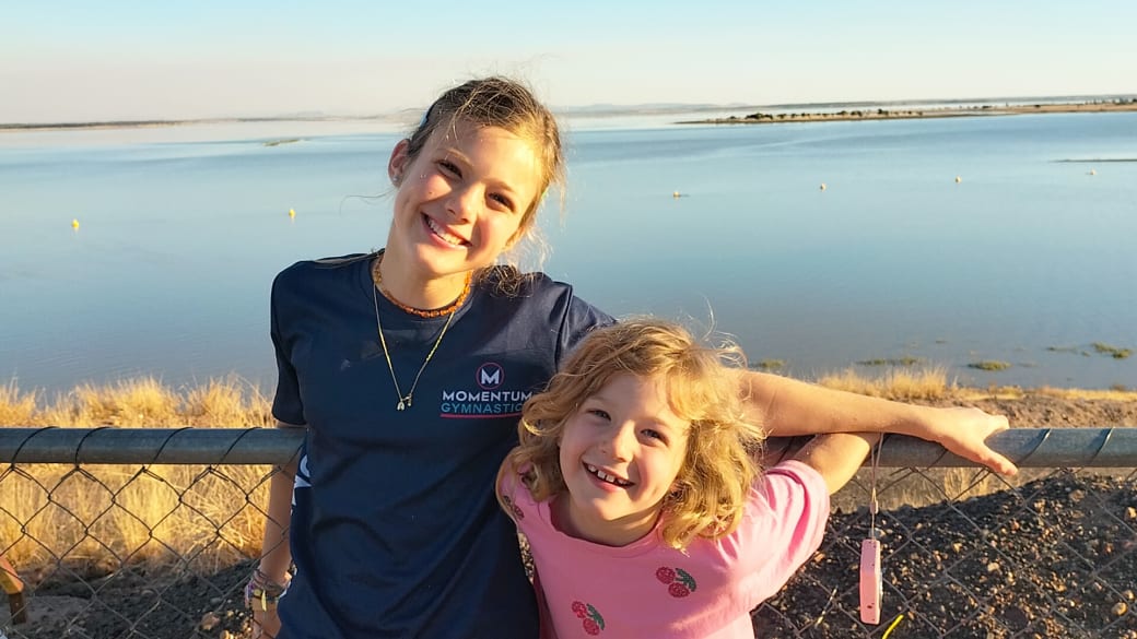 Ayla and Romy smile for a photo at the Fairbairn Dam Lookout, with the tranquil waters of Lake Maraboon behind.