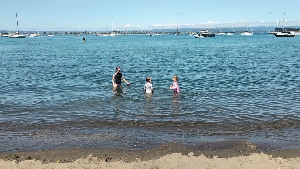 Ayla and Romy swimming with their cousin in the calm waters of Pilot Bay at Mount Maunganui near Tauranga.