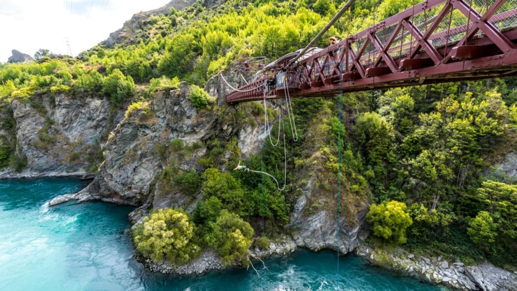 Daring bungee jump over turquoise river in lush green gorge from iconic Kawarau Bridge.