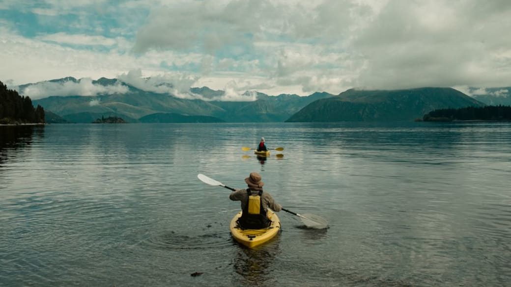 Two kayakers enjoy serene views on the picturesque Lake Wānaka in New Zealand.