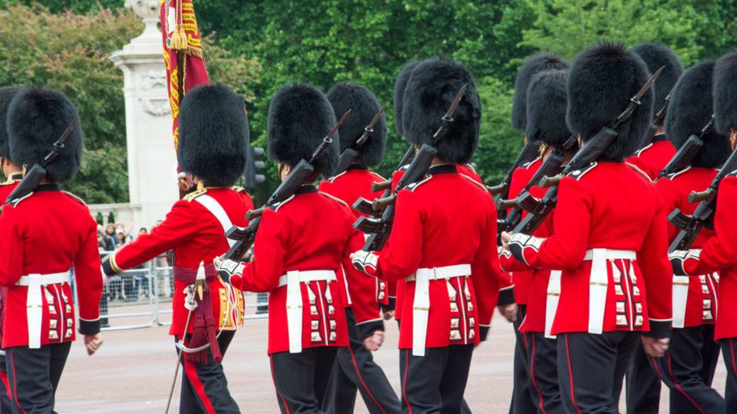 British Queen's Guards march with rifles during a Buckingham Palace ceremony.