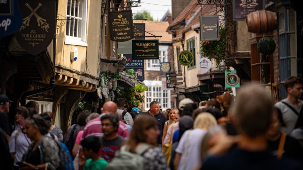 Vibrant and historic Shambles street in York, filled with people and charming shop signs.