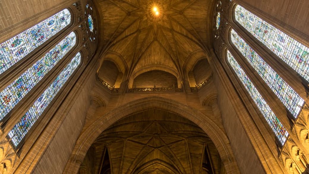 Low angle view of Liverpool Cathedral's interior showcasing stunning stained glass windows and vaulted arches.