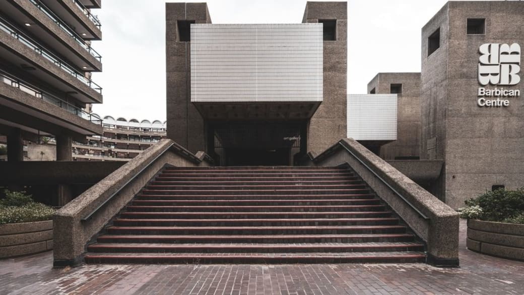 Modern brutalist architecture of Barbican Centre in London featuring iconic concrete design and stairs.