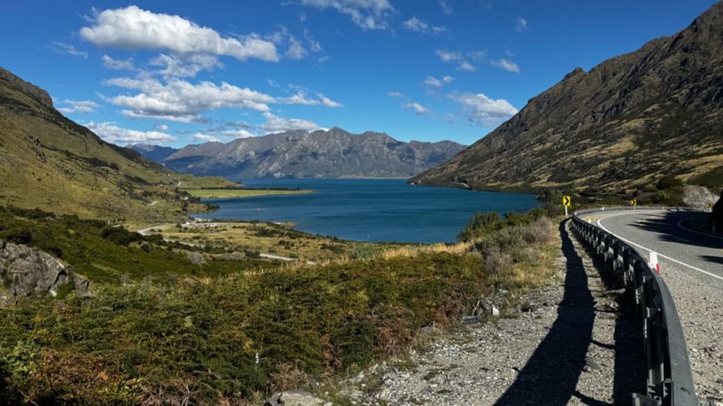 Serene landscape featuring Lake Hawea surrounded by mountains under a clear blue sky.