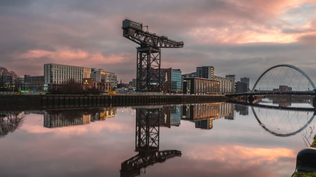 Sunset view of Glasgow's River Clyde, featuring iconic structures and reflections.